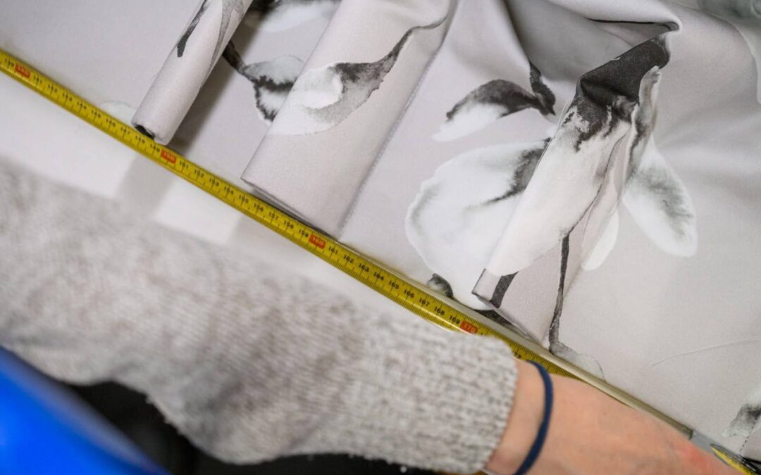 Person measuring floral fabric with a tape measure