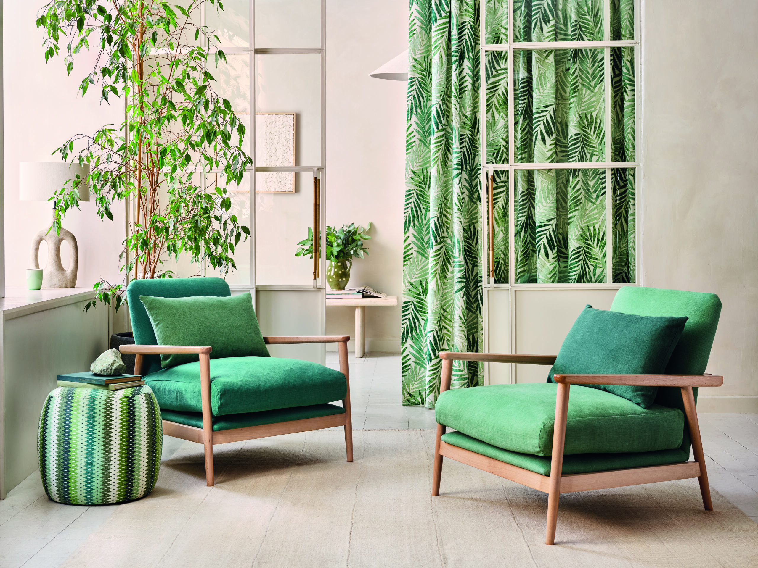 Green chairs in a modern living room with tropical patterned curtains