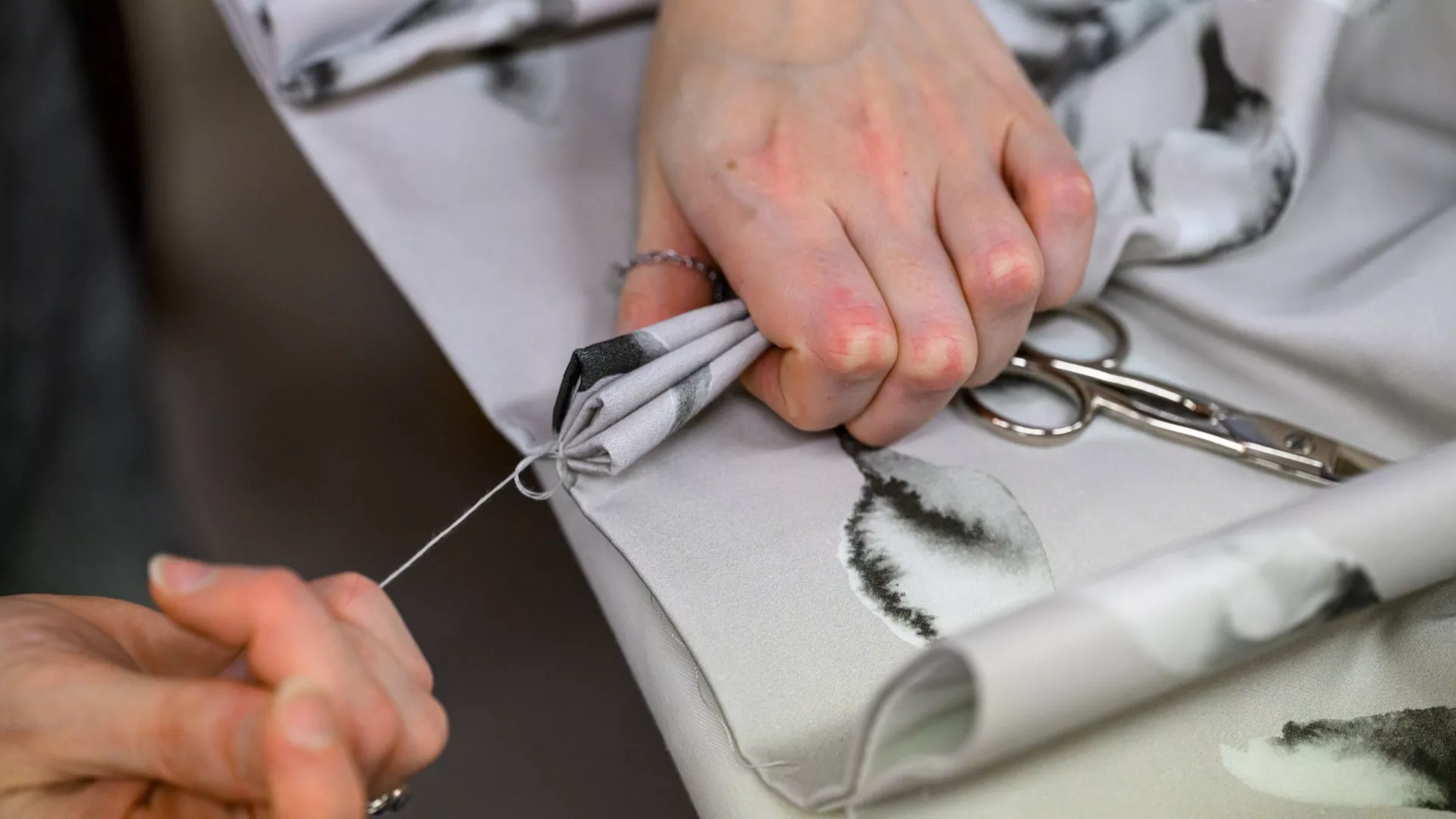 Hand sewing patterned fabric with needle and thread